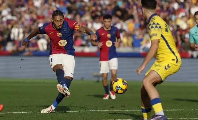 Barcelona's Raphinha kicks a ball challenged by Las Palmas' Mika Marmol during a Spanish La Liga soccer match at the Lluis Companys Olympic Stadium in Barcelona, Spain, Saturday Nov. 30, 2024. (AP Photo/Joan Monfort)