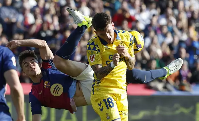 Las Palmas' Viti Rozada, front, and Barcelona's Pedri fight for the ball during a Spanish La Liga soccer match at the Lluis Companys Olympic Stadium in Barcelona, Spain, Saturday Nov. 30, 2024. (AP Photo/Joan Monfort)
