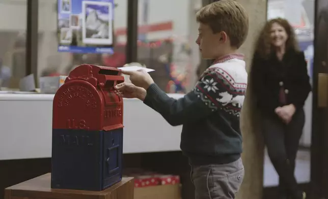 This image released by Disney shows a boy mailing a letter to Santa in a scene from “Dear Santa, The Series." (Disney via AP)