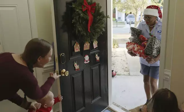 This image released by Disney shows a postal worker, right, delivering gifts to a home in a scene from "Dear Santa, The Series." (Disney via AP)