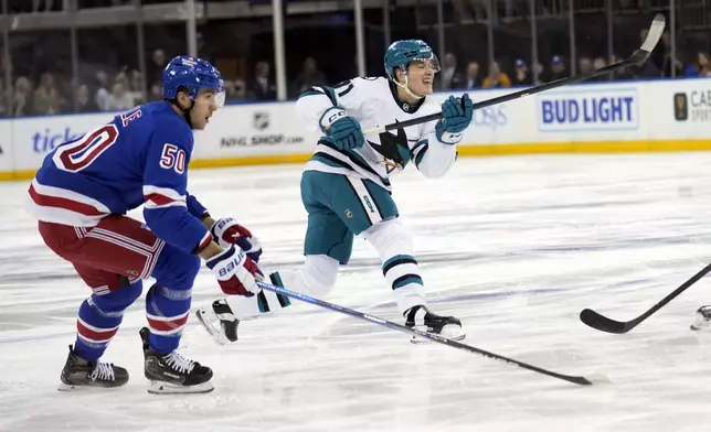 San Jose Sharks' Macklin Celebrini, right, takes a shot on goal while New York Rangers' Will Cuylle looks on during the first period of an NHL hockey game Thursday, Nov. 14, 2024, in New York. (AP Photo/Seth Wenig)