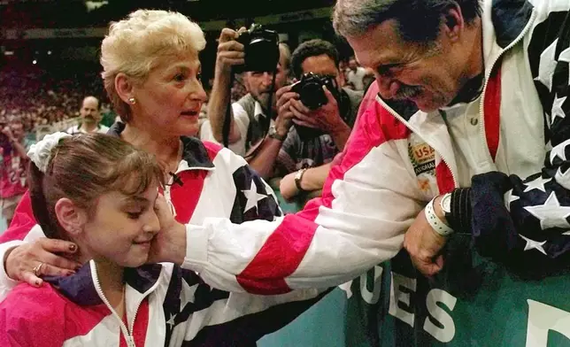 FILE - Bela Karolyi, right, congratulates Dominique Moceanu, left, after the United States captured the gold medal in the women's team gymnastics competition at the Centennial Summer Olympic Games in Atlanta, July 23, 1996. (AP Photo/Amy Sancetta, File)