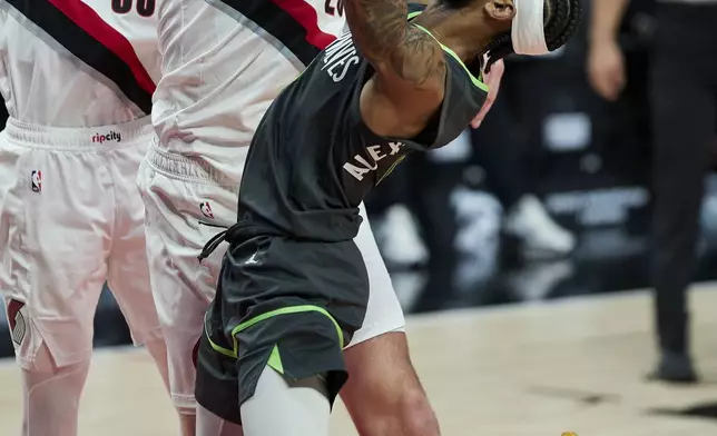 Minnesota Timberwolves guard Nickeil Alexander-Walker, right, shoots over Portland Trail Blazers center Donovan Clingan, center, and forward Toumani Camara during the second half of an NBA basketball game in Portland, Ore., Wednesday, Nov. 13, 2024. (AP Photo/Craig Mitchelldyer)