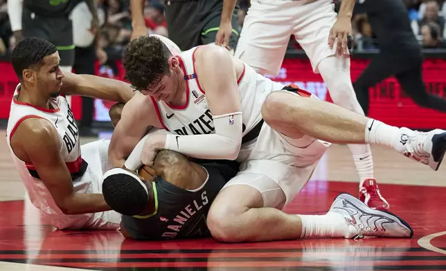 Portland Trail Blazers center Donovan Clingan, right, forward Kris Murray, left, and Minnesota Timberwolves forward Jaden McDaniels dive for a loose ball during the second half of an NBA basketball game in Portland, Ore., Wednesday, Nov. 13, 2024. (AP Photo/Craig Mitchelldyer)