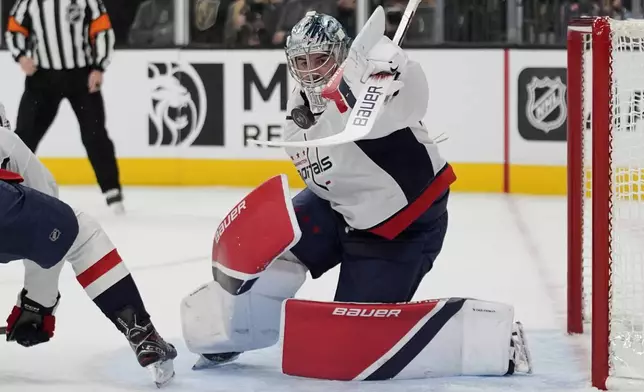 Washington Capitals goaltender Logan Thompson (48) attempts to knock the puck away against the Vegas Golden Knights during the second period of an NHL hockey game Sunday, Nov. 17, 2024, in Las Vegas. (AP Photo/John Locher)