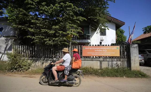 Tourists ride on a motorbike near the tourism control police station in Vang Vieng, Laos, Friday, Nov. 22, 2024. (AP Photo/Anupam Nath)