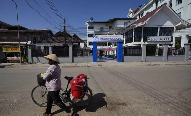 A woman with a bicycle walks pasts Nana Backpackers hostel in Vang Vieng, Laos, Friday, Nov. 22, 2024. (AP Photo/Anupam Nath)