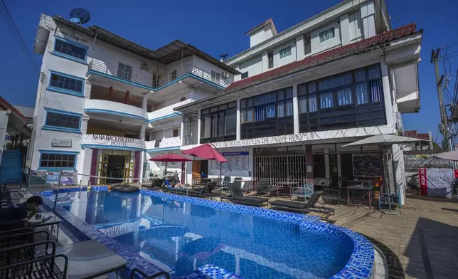 A foreign tourist couple rest near a swimming pool at Nana Backpackers hostel in Vang Vieng, Laos, Friday, Nov. 22, 2024. (AP Photo/Anupam Nath)