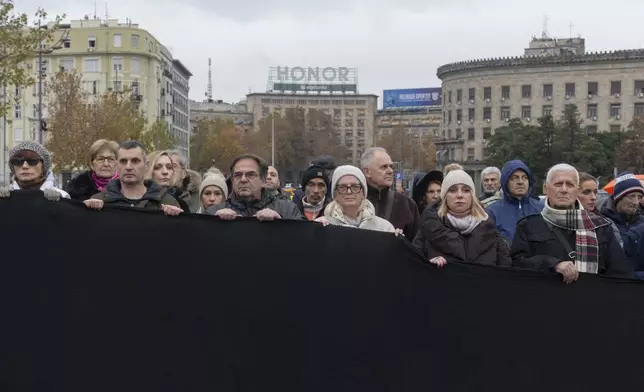 People hold a black banner and stand in silence to commemorate the 15 victims of a railway station roof collapse in Belgrade, Serbia, Friday, Nov. 29, 2024. (AP Photo/Marko Drobnjakovic)