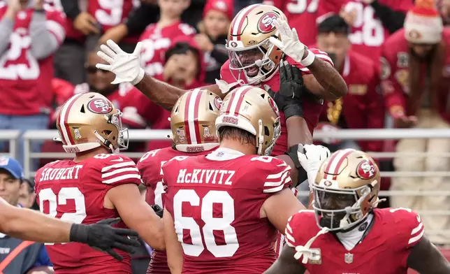 San Francisco 49ers wide receiver Jauan Jennings, top, is congratulated by teammates after scoring against the Seattle Seahawks during the second half of an NFL football game in Santa Clara, Calif., Sunday, Nov. 17, 2024. (AP Photo/Godofredo A. Vásquez)