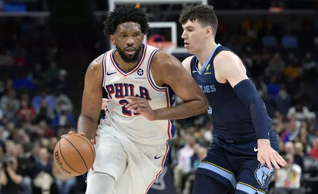 Philadelphia 76ers center Joel Embiid (21) handles the ball against Memphis Grizzlies forward Jake LaRavia in the second half of an NBA basketball game Wednesday, Nov. 20, 2024, in Memphis, Tenn. (AP Photo/Brandon Dill)