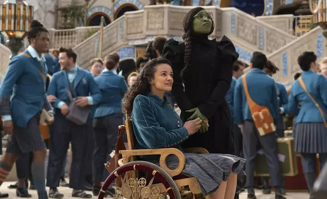 his image released by Universal Pictures shows Marissa Bode, seated center, and Cynthia Erivo in a scene from the film "Wicked." (Universal Pictures via AP)