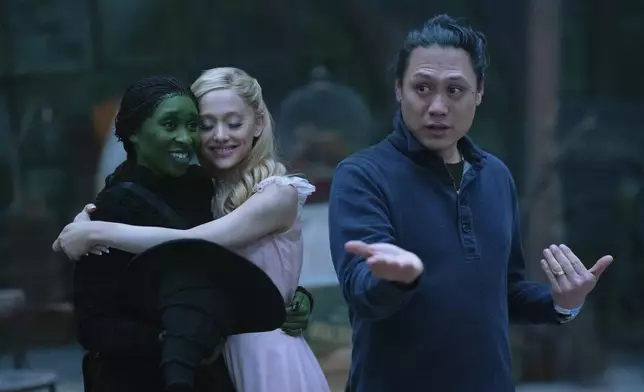 This image released by Universal Pictures shows Cynthia Erivo, left, and Ariana Grande, with director Jon M. Chu, right, on the set of the film "Wicked." (Universal Pictures via AP)