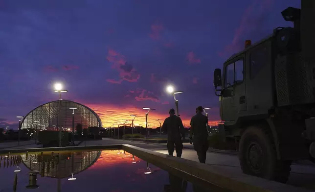 Soldiers walk by a military truck at sunset in Valencia after floods left hundreds dead or missing in the Valencia region in Spain, Tuesday, Nov. 12, 2024. (AP Photo/Alberto Saiz)