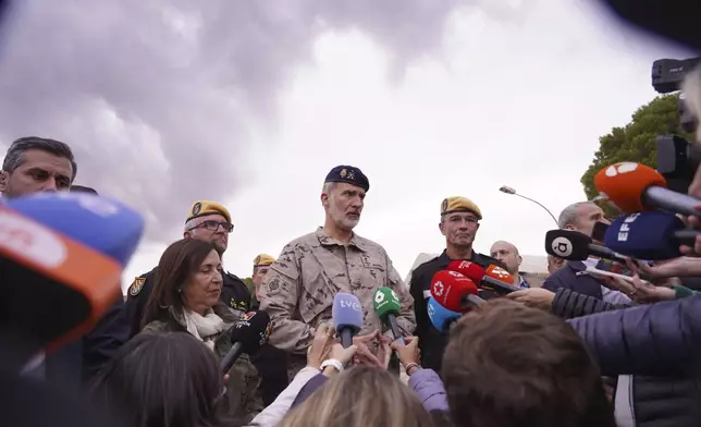 Spain's King Felipe VI speaks with journalists after a visit to a military base with Spain's Defense Minister Margarita Robles, centre left, on the outskirts of Valencia after floods left hundreds dead or missing in the Valencia region in Spain, Tuesday, Nov. 12, 2024. (AP Photo/Alberto Saiz)