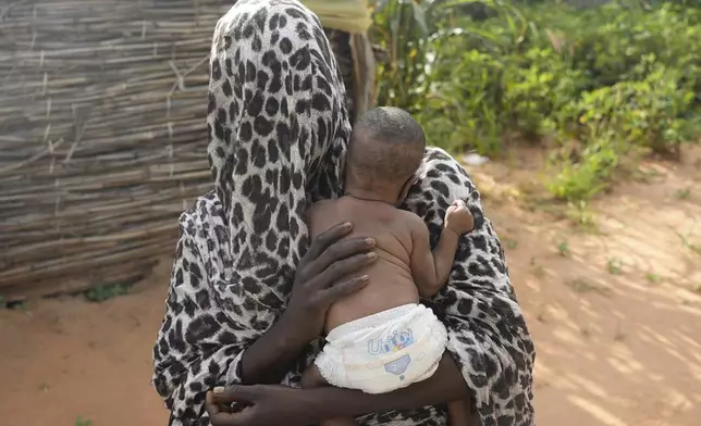 A woman who fled war in Sudan and requested anonymity because she feared retribution after reporting sexual exploitation, holds her baby in a refugee camp in Adre, Chad, Saturday, Oct. 5, 2024. (AP Photo/Sam Mednick)