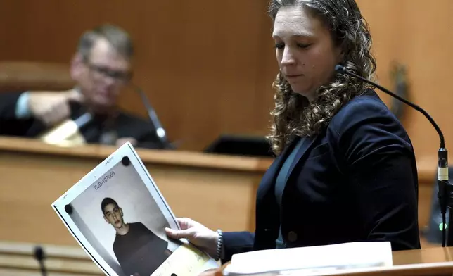 Assistant Attorney General Audriana Mekula holds a picture of alleged victim Michael Gilpatrick when he was 14 that she showed the jury during opening statements in the trial of Bradley Asbury at Hillsborough County Superior Court in Manchester, N.H.,, Tuesday, Nov. 19, 2024. (David Lane/Union Leader via AP, Pool)