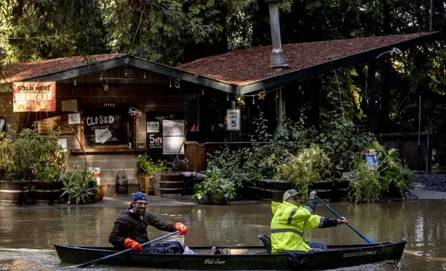 Kevin Ozorkiewicz, left, and neighbor John Phillips row a canoe at the flooded Mirabel RV Park &amp; Campground after a major storm in Forestville, Calif., Sonoma County, Saturday, Nov. 23, 2024. (Stephen Lam/San Francisco Chronicle via AP)