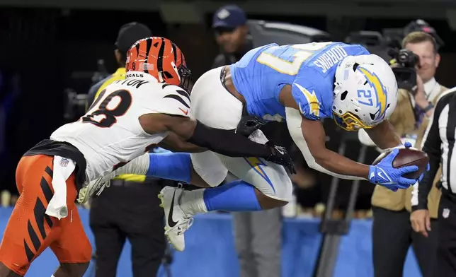 Los Angeles Chargers running back J.K. Dobbins (27) jumps into the end zone to score a rushing touchdown past Cincinnati Bengals cornerback Josh Newton (28) during the second half of an NFL football game Sunday, Nov. 17, 2024, in Inglewood, Calif. (AP Photo/Gregory Bull)