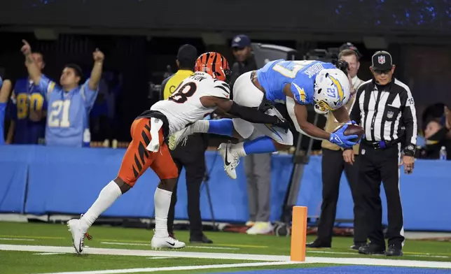 Los Angeles Chargers running back J.K. Dobbins (27) jumps into the end zone to score a rushing touchdown past Cincinnati Bengals cornerback Josh Newton (28) during the second half of an NFL football game Sunday, Nov. 17, 2024, in Inglewood, Calif. (AP Photo/Gregory Bull)