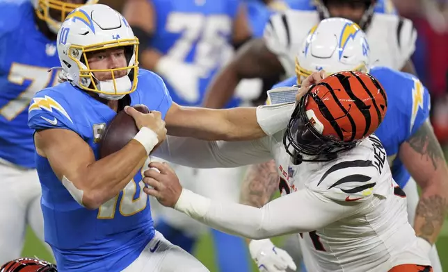 Los Angeles Chargers quarterback Justin Herbert (10) is pressured by Cincinnati Bengals defensive end Trey Hendrickson (91) during the first half of an NFL football game Sunday, Nov. 17, 2024, in Inglewood, Calif. (AP Photo/Gregory Bull)