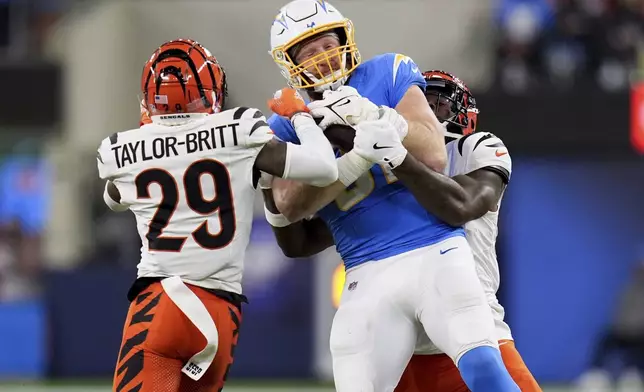 Los Angeles Chargers tight end Will Dissly (81) is tackled by Cincinnati Bengals cornerback Cam Taylor-Britt (29) and linebacker Germaine Pratt during the first half of an NFL football game Sunday, Nov. 17, 2024, in Inglewood, Calif. (AP Photo/Gregory Bull)