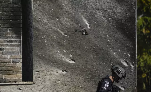 A police bomb squad officer inspects the site where a rocket fired from Lebanon landed in a backyard in Kiryat Shmona, northern Israel, Tuesday Nov. 26, 2024. (AP Photo/Leo Correa)