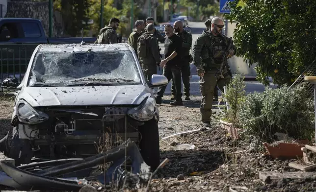 Israeli security officers and army soldiers inspect the site where a rocket fired from Lebanon landed in a backyard in Kiryat Shmona, northern Israel, Tuesday Nov. 26, 2024. (AP Photo/Leo Correa)