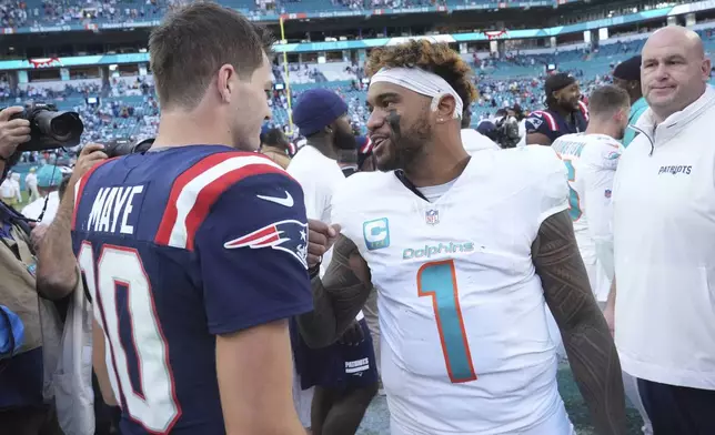 New England Patriots quarterback Drake Maye (10) and Miami Dolphins quarterback Tua Tagovailoa (1) meet at the end an NFL football game, Sunday, Nov. 24, 2024, in Miami Gardens, Fla. (AP Photo/Wilfredo Lee)