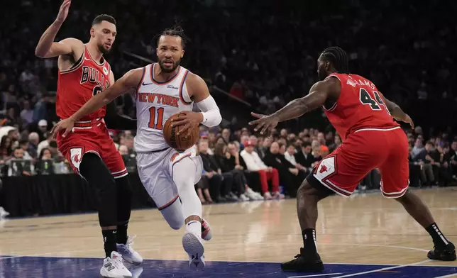 New York Knicks' Jalen Brunson, center, drives to the basket through Chicago Bulls' Zach LaVine, left, and Patrick Williams during the first half of an NBA basketball game, Wednesday, Nov. 13, 2024, in New York. (AP Photo/Seth Wenig)