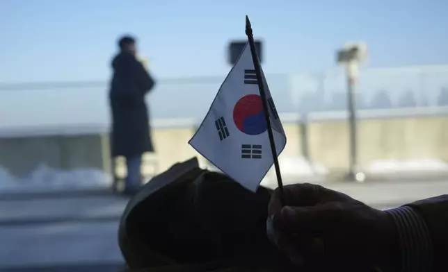 A visitor holds a national flag at newly opened Starbucks store at the observatory of the Aegibong Peace Ecopark in Gimpo, South Korea, Friday, Nov. 29, 2024. (AP Photo/Lee Jin-man)