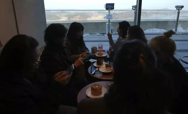 Visitors sit at a newly opened Starbucks store as North Korea's Kaephung county is seen in the background at the observatory of the Aegibong Peace Ecopark in Gimpo, South Korea, Friday, Nov. 29, 2024. (AP Photo/Lee Jin-man)