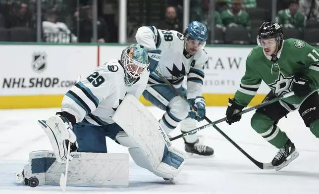 San Jose Sharks goaltender Mackenzie Blackwood (29) deflects a shot under pressure from Dallas Stars center Logan Stankoven (11) as defenseman Mario Ferraro (38) looks on in the first period of an NHL hockey game in Dallas, Wednesday, Nov. 20, 2024. (AP Photo/Tony Gutierrez)