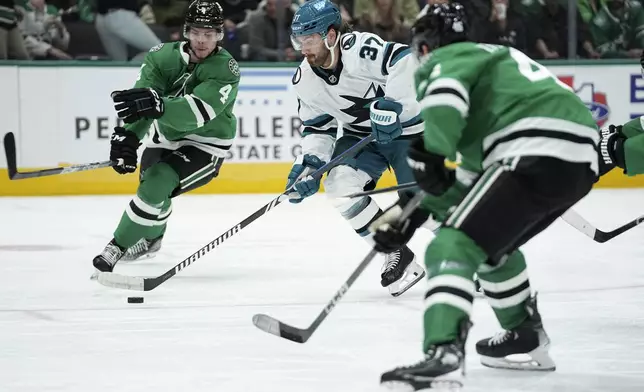 San Jose Sharks defenseman Timothy Liljegren (37) positions to shoot as Dallas Stars' Miro Heiskanen (4) and Ilya Lyubushkin, right, defend in the second period of an NHL hockey game in Dallas, Wednesday, Nov. 20, 2024. (AP Photo/Tony Gutierrez)