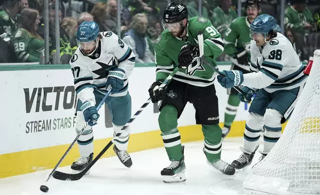 San Jose Sharks defenseman Timothy Liljegren (37) and defenseman Mario Ferraro (38) work to take control of the puck under pressure from Dallas Stars center Tyler Seguin (91) in the first period of an NHL hockey game in Dallas, Wednesday, Nov. 20, 2024. (AP Photo/Tony Gutierrez)