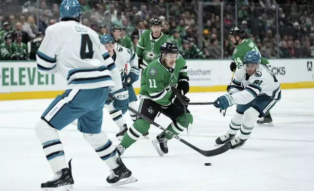 Dallas Stars center Logan Stankoven (11) handles the puck as he works against San Jose Sharks defenders Cody Ceci (4) and Alexander Wennberg (21) in the first period of an NHL hockey game in Dallas, Wednesday, Nov. 20, 2024. (AP Photo/Tony Gutierrez)