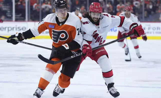 Philadelphia Flyers' Owen Tippett, left, and Carolina Hurricanes' Jalen Chatfield chase after the puck during the second period of an NHL hockey game, Wednesday, Nov. 20, 2024, in Philadelphia. (AP Photo/Matt Slocum)