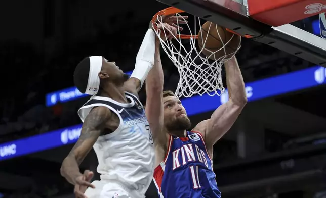 Sacramento Kings forward Domantas Sabonis (11) dunks while Minnesota Timberwolves forward Jaden McDaniels (3) defends during the first half of an NBA basketball game, Wednesday, Nov. 27, 2024, in Minneapolis. (AP Photo/Ellen Schmidt)