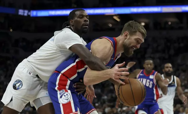 Minnesota Timberwolves center Naz Reid, left, fouls Sacramento Kings forward Domantas Sabonis during the first half of an NBA basketball game, Wednesday, Nov. 27, 2024, in Minneapolis. (AP Photo/Ellen Schmidt)