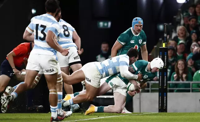 Ireland's Mack Hansen, right, scires a try during the Autumn Nations series rugby union match between Ireland and Argentina, at Aviva Stadium, Dublin, Ireland, Friday, Nov. 15, 2024. (AP Photo/Peter Morrison)