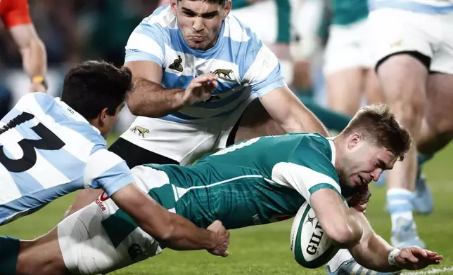 Ireland's Jack Crowley, right, scores a try as Argentina's Lucio Cinti tries to defend during the Autumn Nations series rugby union match between Ireland and Argentina, at Aviva Stadium, Dublin, Ireland, Friday, Nov. 15, 2024. (AP Photo/Peter Morrison)