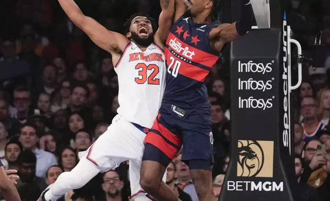 New York Knicks' Karl-Anthony Towns (32), left, is fouled by Washington Wizards' Alexandre Sarr during the first half of an NBA basketball game, Monday, Nov. 18, 2024, in New York. (AP Photo/Seth Wenig)