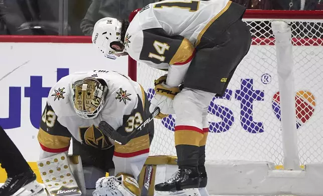 Vegas Golden Knights defenseman Nicolas Hague, right, checks on goaltender Adin Hill after he was injured in a collision with an Colorado Avalanche player in the second period of an NHL hockey game Wednesday, Nov. 27, 2024, in Denver. (AP Photo/David Zalubowski)