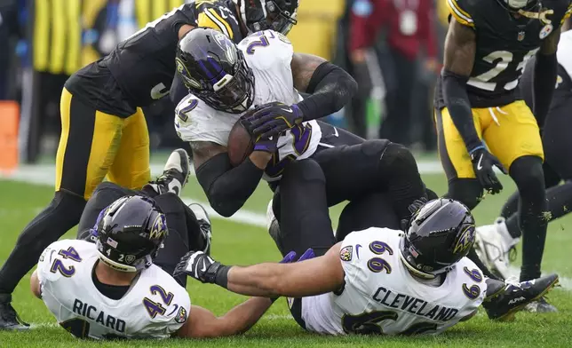 Baltimore Ravens running back Derrick Henry (22) scores a touchdown as Pittsburgh Steelers safety Minkah Fitzpatrick, top left, and safety DeShon Elliott, top right, try to stop him during the first half of an NFL football game, Sunday, Nov. 17, 2024, in Pittsburgh. Ravens' Patrick Ricard (42) and Ben Cleveland (66) hit the ground on the play. (AP Photo/Matt Freed)