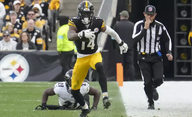 Pittsburgh Steelers wide receiver George Pickens (14) avoids a tackle by Baltimore Ravens cornerback Brandon Stephens (21) during the second half of an NFL football game, Sunday, Nov. 17, 2024, in Pittsburgh. (AP Photo/Gene J. Puskar)