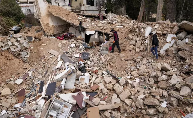 Displaced residents walk on the rubble of their destroyed house in Baalbek, eastern Lebanon, Thursday, Nov. 28, 2024. (AP Photo/Hassan Ammar)