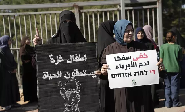 Women hold Arabic placards that read, "Gaza children deserve life," left, and "stop shedding innocent blood," as Palestinian citizens of Israel march against Israel's military operations in the Gaza Strip, in Umm al-Fahm, Israel, Friday, Nov. 15, 2024. (AP Photo/Mahmoud Illean)