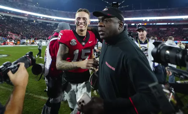 Georgia quarterback Carson Beck (15) and assistant coach Josh Crawford run off the field after defeating Tennessee in an NCAA college football game, Saturday, Nov. 16, 2024, in Athens, Ga. (AP Photo/John Bazemore)