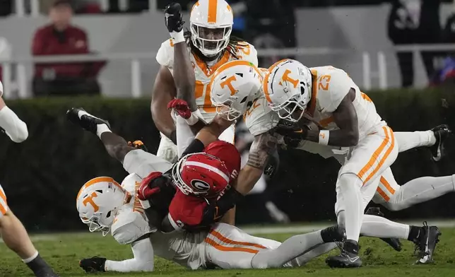 Georgia running back Nate Frazier (3) is stopped by Tennessee defensive back Andre Turrentine (2), defensive back Boo Carter (23) and linebacker Jeremiah Telander (22) during the first half of an NCAA college football game, Saturday, Nov. 16, 2024, in Athens, Ga. (AP Photo/John Bazemore)