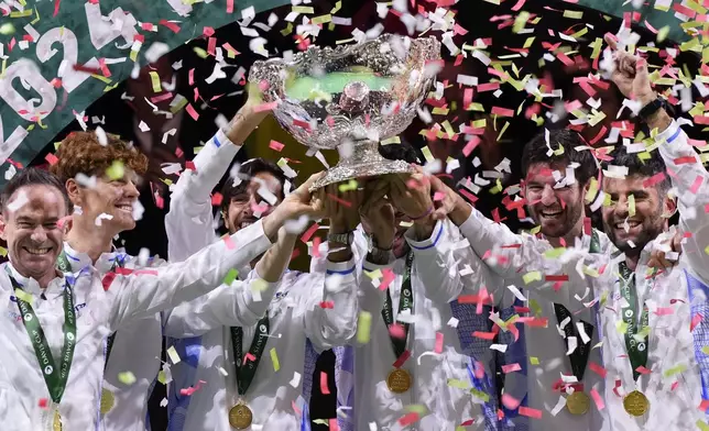 Italian tennis team members hold the Davis Cup trophy after the final between Netherlands and Italy at the Martin Carpena Sports Hall in Malaga, southern Spain, as Italy wins its second consecutive Davis Cup title, Sunday, Nov. 24, 2024. (AP Photo/Manu Fernandez)